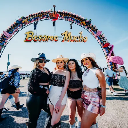 Four fans in cowboy hats under the Besame Mucho festival entry arch