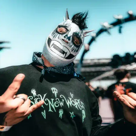 A fan in a luchador mask wearing a Sick New World shirt