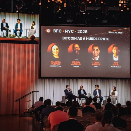A panel on stage at the Bitcoin conference in New York, the session title on the screen behind them