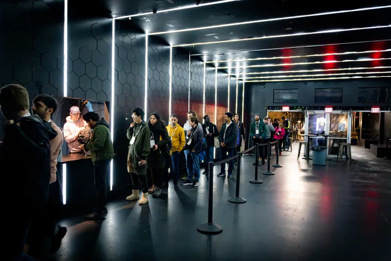Guests waiting in a stanchioned line at an event check-in desk, with staff scanning badges under neon strip lighting.
