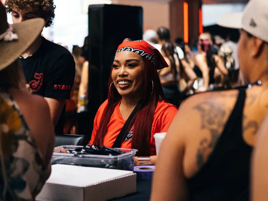 A Jampack staff member in a branded bandana smiling at guests across the check-in desk